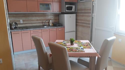 une cuisine avec une table, des chaises et une table avec des fruits. dans l'établissement Andi Apartman, à Pačir