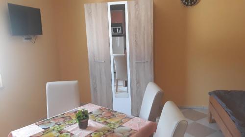 - une salle à manger avec une table, des chaises et un miroir dans l'établissement Andi Apartman, à Pačir