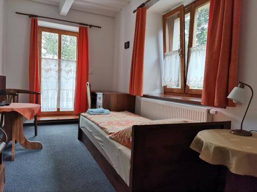a bedroom with a bed with red curtains and a table at Penzion Pod Zámkem in Zruč nad Sázavou