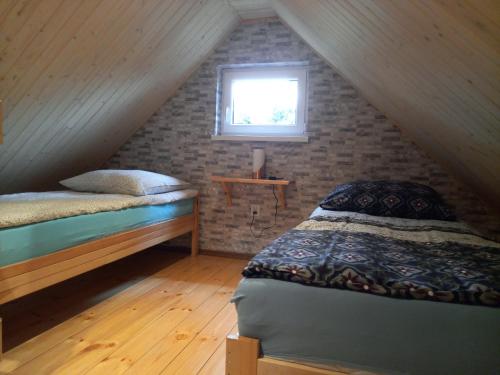 a attic bedroom with two beds and a window at Agroturystyka pod świerkami in Ryn