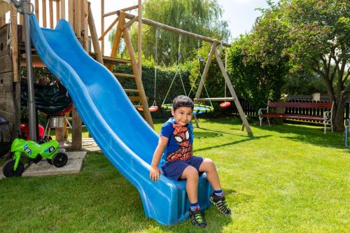 a young boy sitting on a slide in a playground at Privatzimmer Haus Gschweitl in Semriach