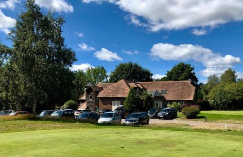 a house with cars parked in a parking lot at Sedlescombe Golf Hotel in Sedlescombe