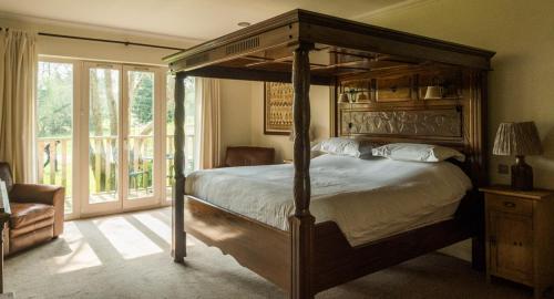 a bedroom with a large bed with a wooden canopy at Sedlescombe Golf Hotel in Sedlescombe