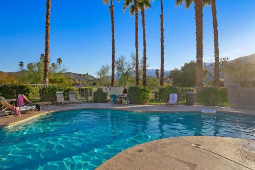 a swimming pool with palm trees in a resort at Our Mesquite-Refreshed 1st floor nature preserve & mtn view condo! in Palm Springs