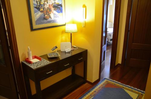 Habitación con escritorio con lámpara y pared amarilla. en Apartamento en Beiramar, en O Grove