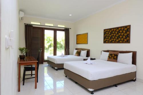 a bedroom with two beds and a table and a desk at Taman Bukit Palem Resort in Bogor