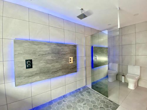 a bathroom with a toilet and a wall with blue lights at Fabrik Apartments - Harrowside by Blackpool Service Apartements in Blackpool