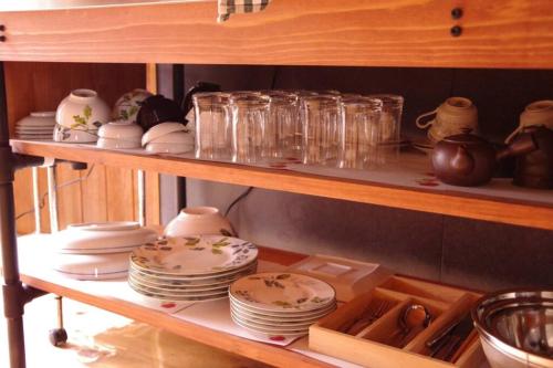 a shelf with plates and cups and dishes on it at Miyajima Breeze in Hatsukaichi