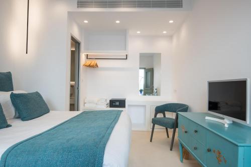 a bedroom with a bed and a desk and a tv at Hotel Senia - Onar Hotels Collection in Naousa