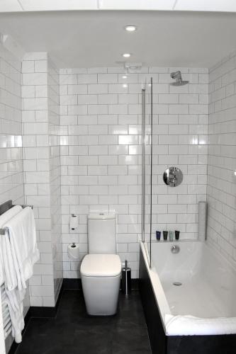 a bathroom with a tub and a toilet and a bath tub at Kings Arms Hotel in Berkhamsted