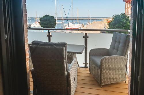 dwa krzesła i stół na balkonie z łodzią w obiekcie Lütt Haven w mieście Barth