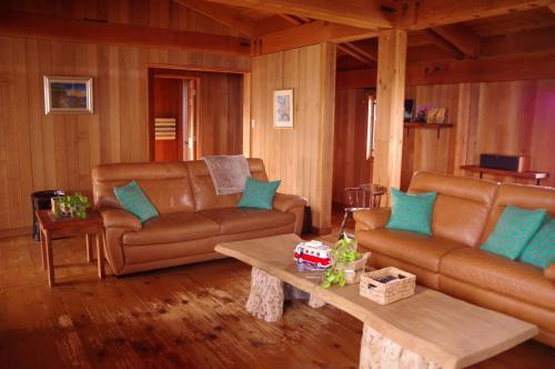 a living room with brown leather couches and a table at Miyajima Breeze in Hatsukaichi