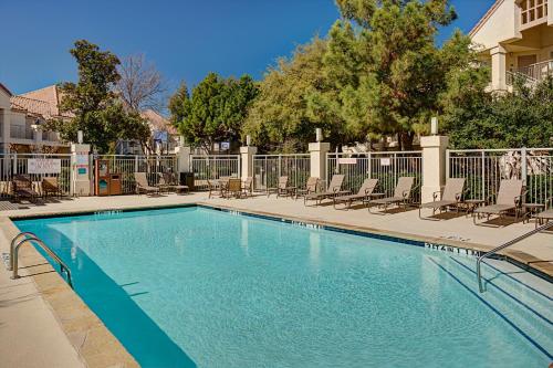 a large swimming pool with chairs and a fence at Hyatt House Dallas Las Colinas in Irving