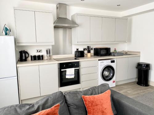 a kitchen with white cabinets and a gray couch at Winter Gardens Service Apartments by Blackpool Service Apartments in Blackpool