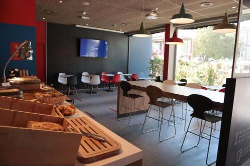 a restaurant with a counter with chairs and a table at Ibis Alès Centre Ville in Alès