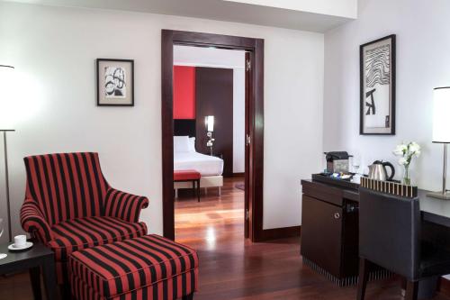 a room with a chair and a desk and a bedroom at NH City Buenos Aires in Buenos Aires