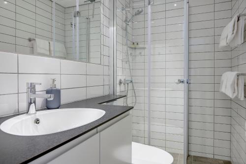 a white bathroom with a sink and a shower at Hotel Siemsens Gaard in Svaneke
