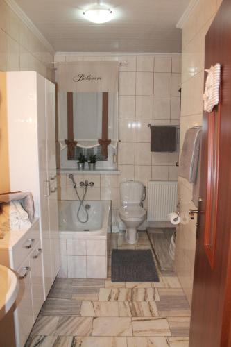 y baño con bañera, aseo y lavamanos. en Pensjonat HANYSEK, en Góra Świętej Anny