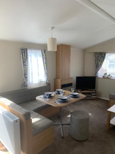 a living room with a table and a couch at Gold Plus 6 Berth Caravan in NEW BEACH with parking WiFi and decking in Dymchurch