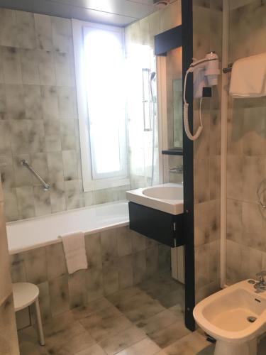a bathroom with a tub and a sink and a shower at Hotel des Mimosas in Juan-les-Pins