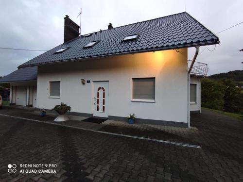 a white house with a black roof at Baranie Wzgórze Ustroń Basen Sauna Plac Zabaw in Cisownica