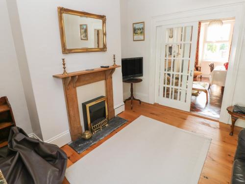 a living room with a fireplace and a tv at Hawthorn House in Pembroke