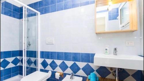 y baño azul y blanco con ducha y lavabo. en Carloforte Bellavista en Carloforte