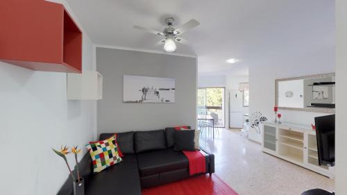 a living room with a black couch and a kitchen at La Castillo in Santa Cruz de Tenerife
