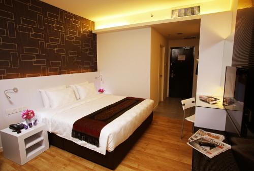 a bedroom with a white bed and white walls at Cairnhill Hotel Kuala Lumpur in Kuala Lumpur