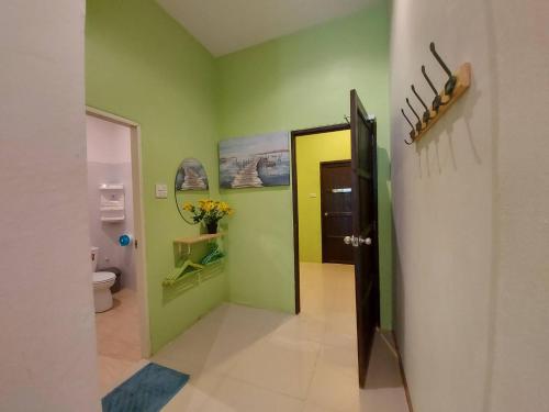 a hallway with a bathroom with green walls and a door at Baan AomSub in Ko Samed