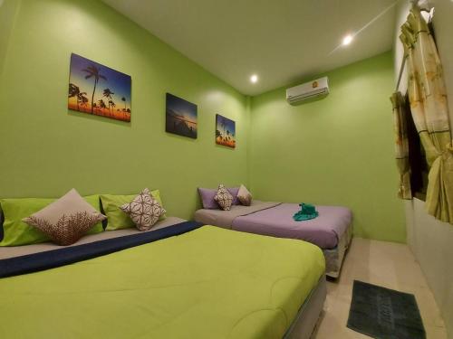 two beds in a room with green walls at Baan AomSub in Ko Samed