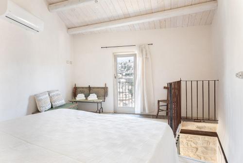 a white bedroom with a bed and a window at Nido di Modica con vista in Modica