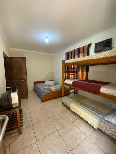 a room with two bunk beds and a tv at Pousada J.C. Cazeri in Santos