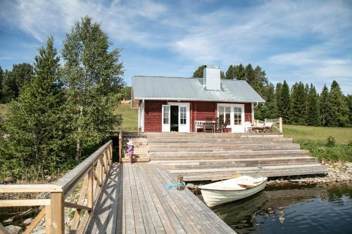 uma pequena casa vermelha com um barco numa doca em Hugsnäset Semesterstugor och Fiske em Gällö