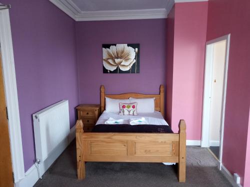 a bedroom with purple walls and a wooden bed at LSO Guest House in Dumfries