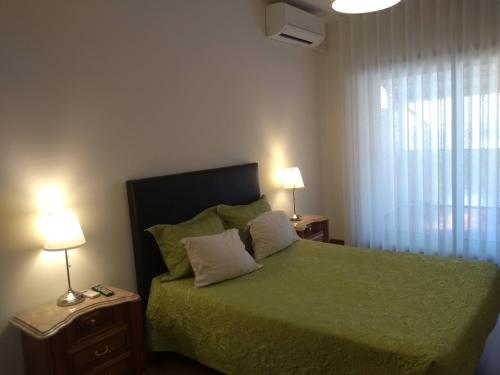 a bedroom with a green bed with two lamps and a window at Alegria Downtown Apartments in Porto