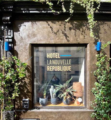 a window with potted plants and a sign in it at Hôtel La Nouvelle République & Hammam in Paris