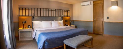 a bedroom with a large bed with a blue blanket at Hacienda Jurica by Brisas in Querétaro