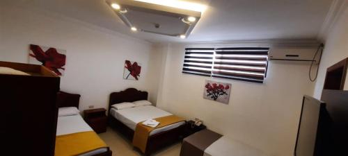 a small room with two beds and a window at Hostal Perla Real Inn in Guayaquil