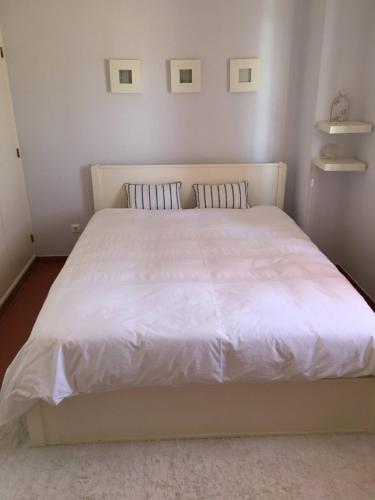 a bedroom with a white bed with two pillows at Casa do Almograve in Almograve