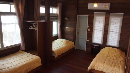a room with two beds in a room with windows at Ban Boonchu in Phra Nakhon Si Ayutthaya