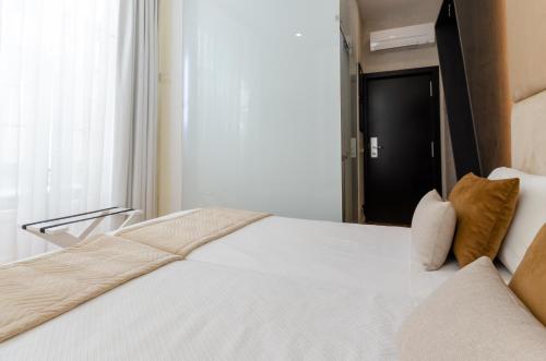 a bedroom with a large white bed with a window at Hotel Duas Nações in Lisbon