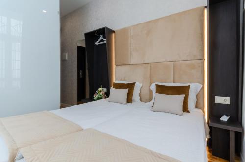a bedroom with two white beds and a large headboard at Hotel Duas Nações in Lisbon