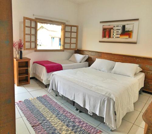 a bedroom with two beds and a window at Hotel Pontal de Tiradentes in Tiradentes