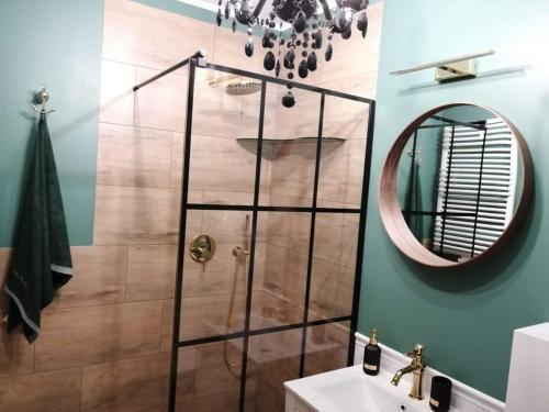 a bathroom with a shower with a sink and a mirror at Luksusowy Apartament nad morzem in Gdańsk