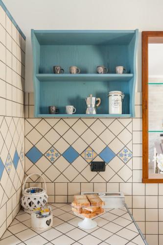 a tiled kitchen with a blue shelf with dishes at Casa Vacanze Giramondo in Fiumicino