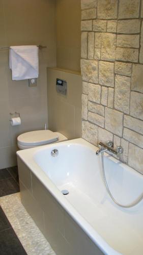 a bathroom with a bath tub and a toilet at Business Wieland Hotel in Düsseldorf