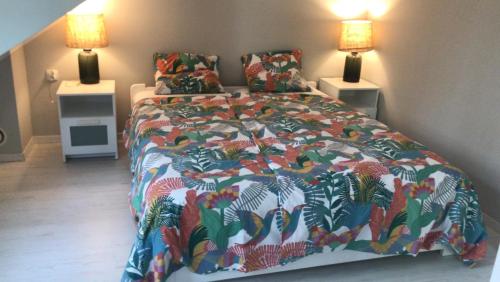 een slaapkamer met een bed met een kleurrijk dekbed en 2 lampen bij Domek wypoczynkowy w lesie nad jeziorem in Ocypel