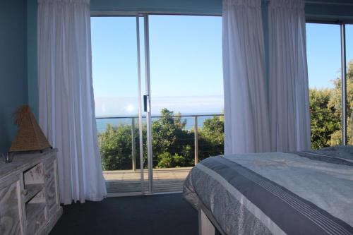 a bedroom with a bed and a view of the ocean at Ungabona in East London