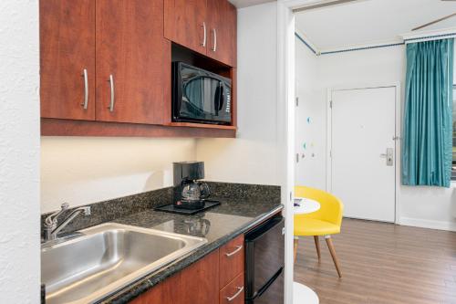 a kitchen with a sink and a microwave at Beachside Hotel and Suites in Cocoa Beach